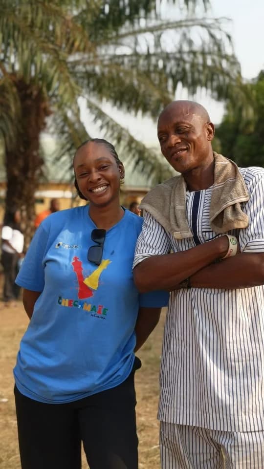 Peace smiling beside a man in a striped traditional outfit
