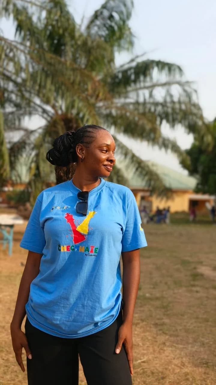 Peace in a blue CHECKMATE by Coderina T-shirt, standing under palm trees at a school